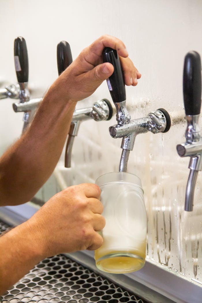 A person pouring a refreshing beer from a tap into a glass at a bar counter.